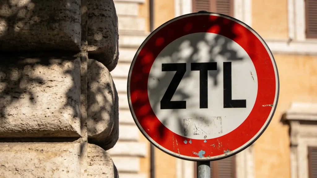 Um sinal de trânsito ZTL italiano desgastado pelo tempo, com a sua borda vermelha característica, à sombra parcial.